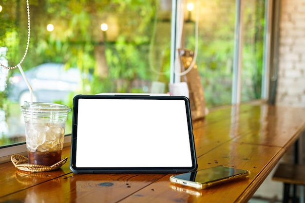 Mockup of digital tablet with empty screen with coffee and smartphone isolate on wooden office desk in coffee shop like the background White screen