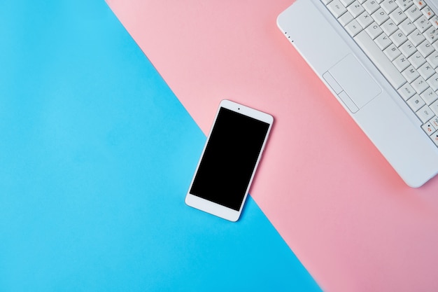 Mockup Flat lay composition with smartphone and laptop on a blue and pink background.