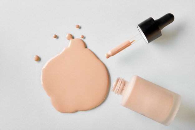 Mockup glass bottle of correction cosmetic product with pipette Spilled Liquid foundation Beauty branding concept