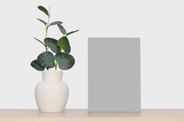 Mockup of a gray book and a gray vase with green eucalyptus branches On a gray background