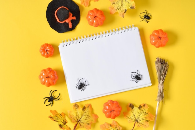 A mockup of a Halloween notebook with pumpkins and spiders on a yellow background with a place for text