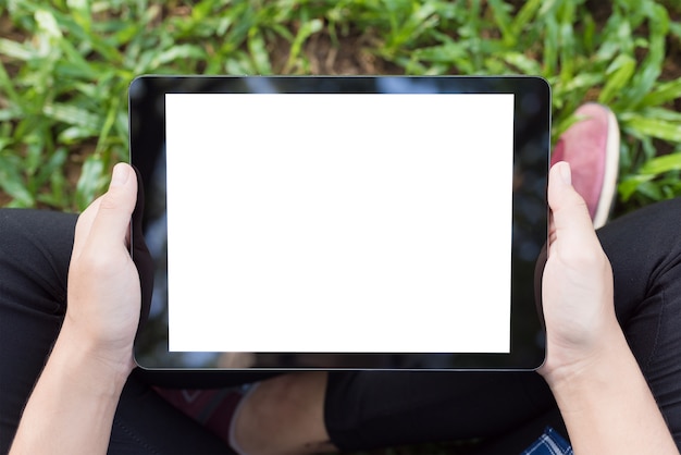 Mockup image of an asian woman sitting and holding black tablet with blank white screen