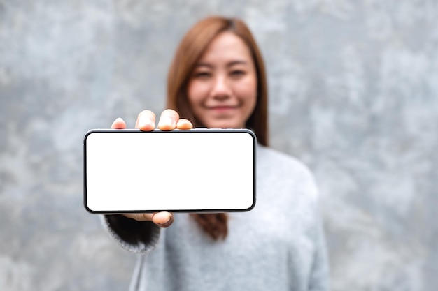 Mockup image of a beautiful woman holding and showing mobile phone with blank white screen