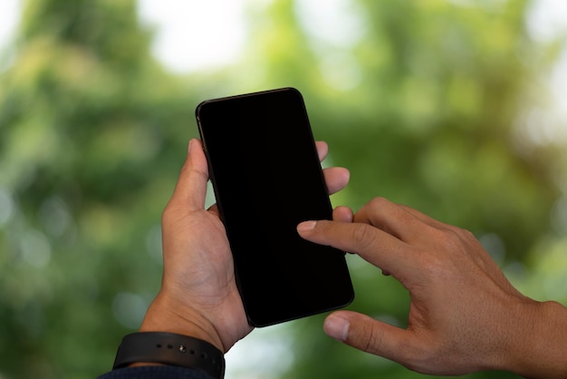 Mockup image of hand holding mobile phone with blank green nature background