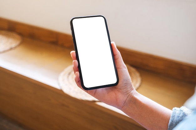 Mockup image of a hand holding mobile phone with blank white desktop screen