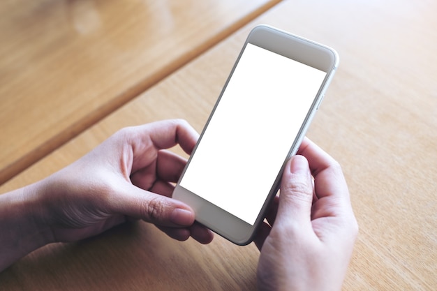 Mockup image of hands holding white mobile phone with blank desktop screen 