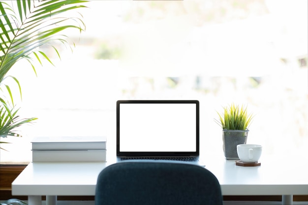 Mockup image of laptop computer with blank white screen on working space at home office