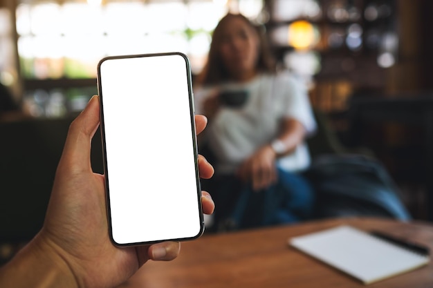 Mockup image of a man holding mobile phone with blank white screen with a woman in background