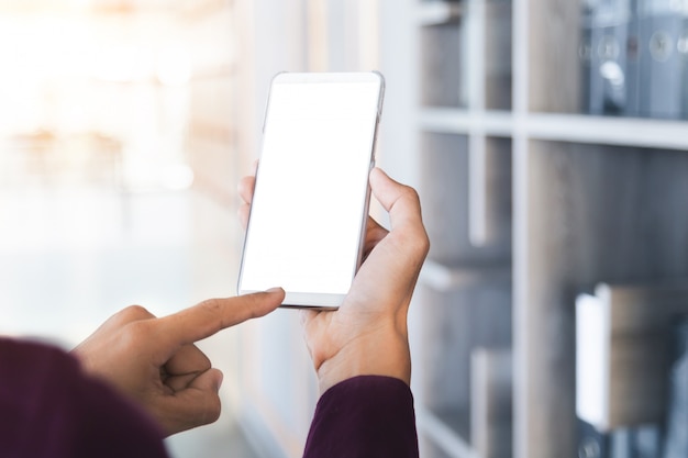 Mockup image of man's hands holding white mobile phone with blank screen technology.