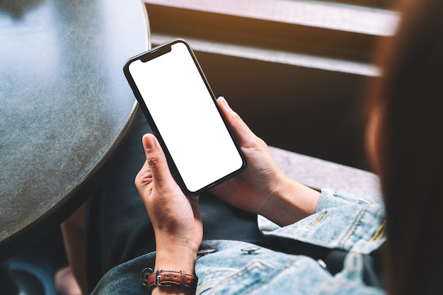 Mockup image of a woman holding black mobile phone with blank desktop screen