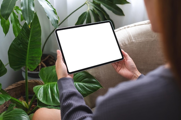 Mockup image of a woman holding digital tablet with blank desktop screen at home