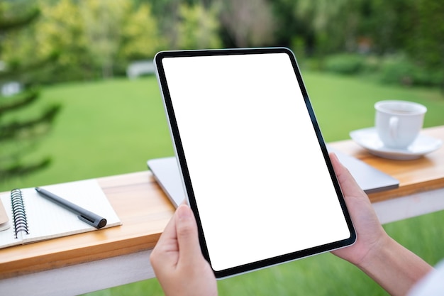 Mockup image of a woman holding digital tablet with blank white desktop screen in the outdoors