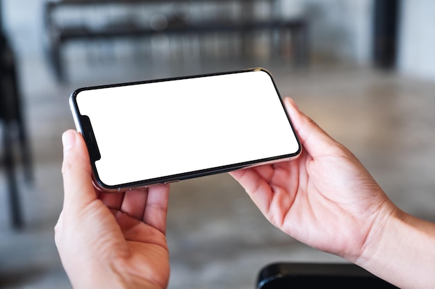 Mockup image of a woman holding mobile phone with blank white desktop screen