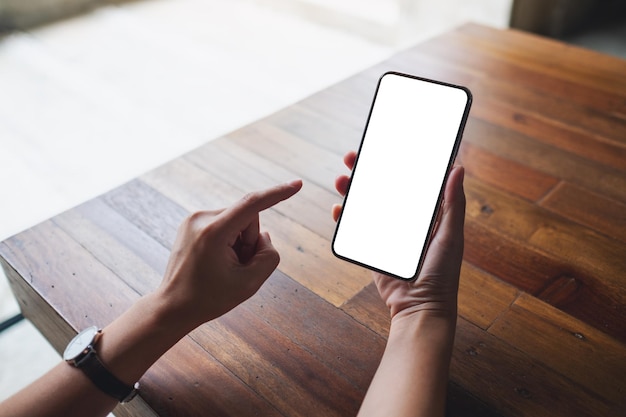 Mockup image of a woman holding mobile phone with blank white desktop screen