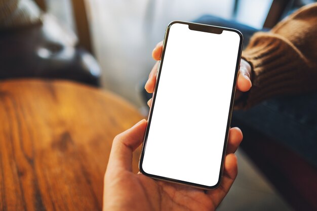 Mockup image of a woman holding and showing white mobile phone with blank black desktop screen to someone