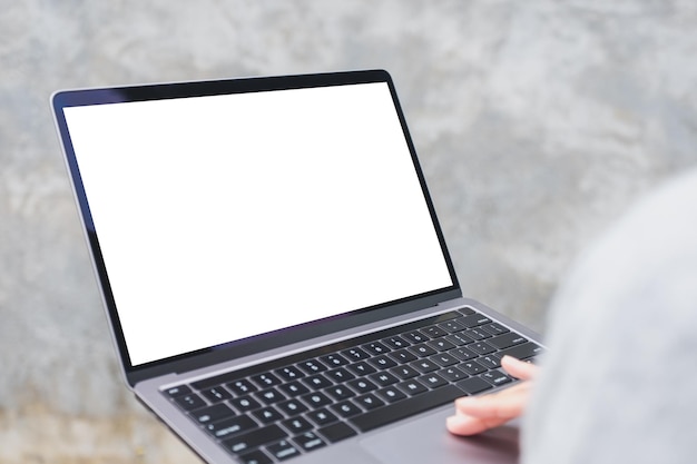 Mockup image of a woman holding and using laptop computer with blank white desktop screen in the outdoors