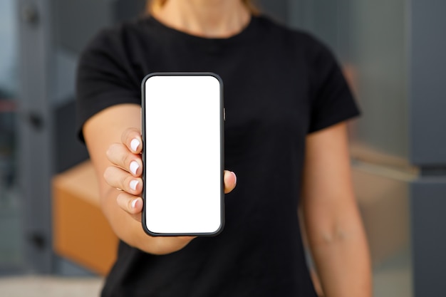 Mockup image. Woman pointing finger at a mobile phone with blank white screen