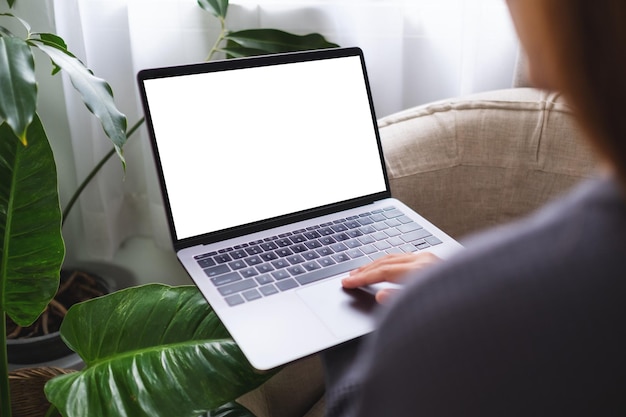 Mockup image of a woman using and working on laptop computer with blank desktop screen at home