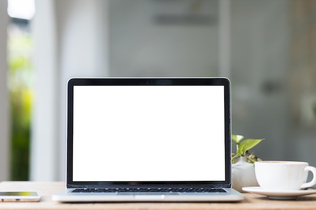 Mockup of laptop computer with empty screen with coffee cup and smartphone on table of the coffee shop backgroundWhite screen