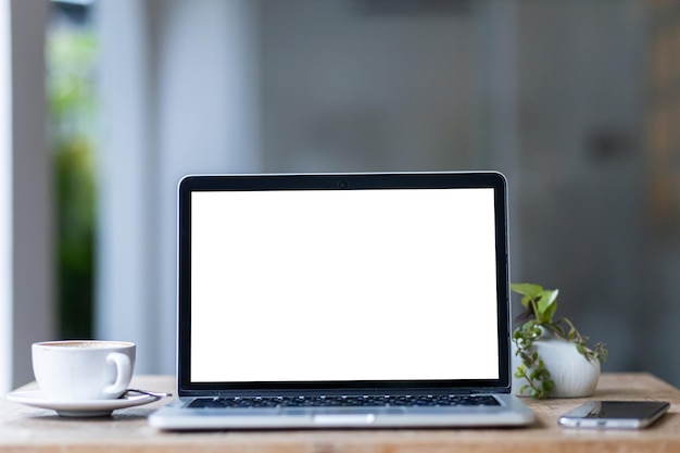 Mockup of laptop computer with empty screen with coffee cup and smartphone on table of the coffee shop backgroundWhite screen