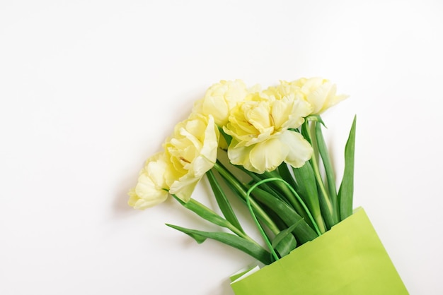 Mockup of a paper shopping bag with tulip flowers lying on a white background Spring Easter sale