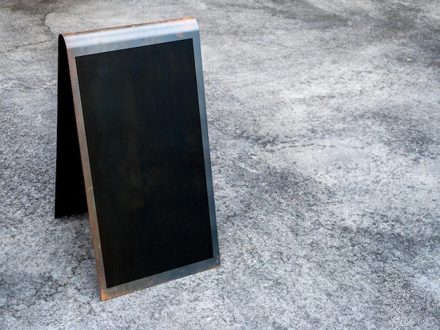 Mockup street tent floor sign outdoor on the ground in front of the restaurant or cafe Black blank square space vertical style frame for information on signage on grunge cement floor background