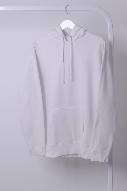 Mockup of a White Hoodie Hanging From a Clothing Rack