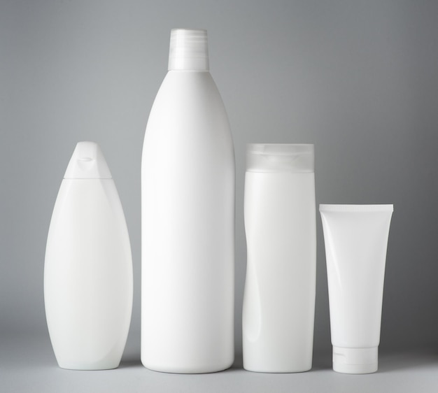 Mockup with set of different white clean shampoo bottles on gray background