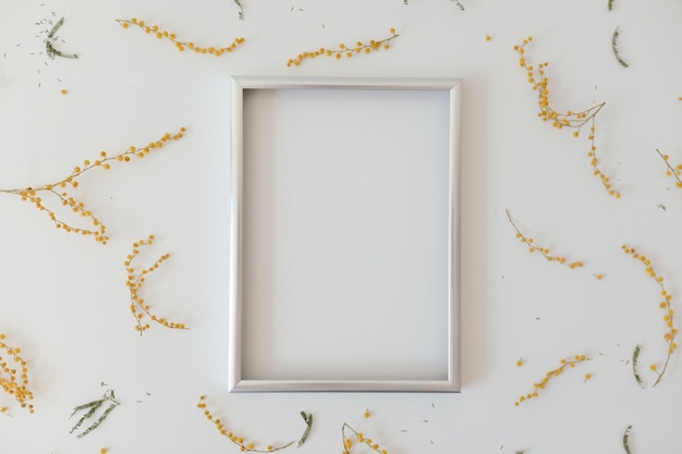 Mockup with yellow mimosa flowers and blank photo frame with copy space spring easter concept