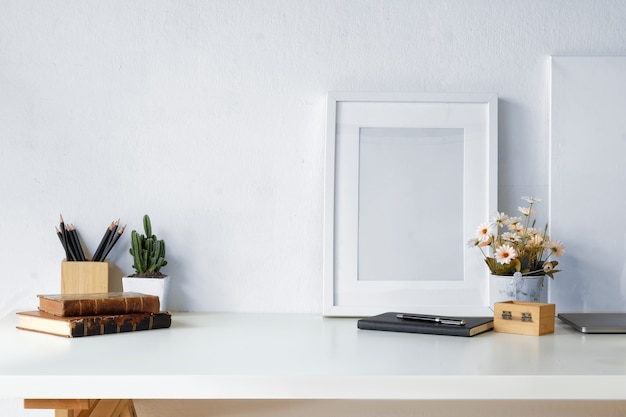 Mockup workspace vintage books, dry flower, office stationery and poster frame