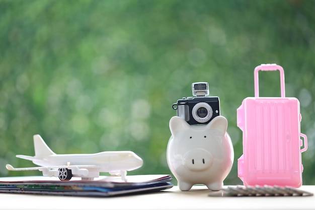 Photo model camera on piggy bank and airplane on natural green backgroundsaving planning for travel budget of holiday conceptfinancial