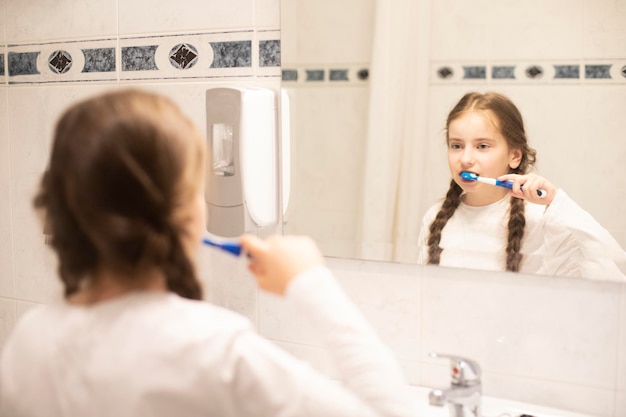 Model child in front of a mirror brushes his teeth Girl with toothbrush place for writing