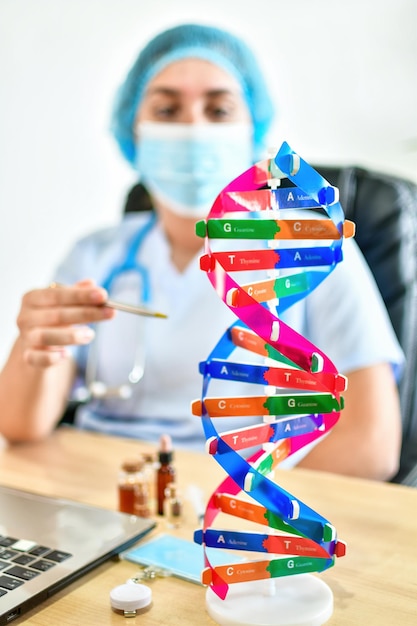 Model of DNA structure near laptop on desk in laboratory