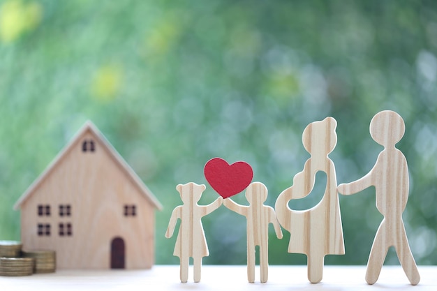 Model family with model house and stack of coins money on natural green background