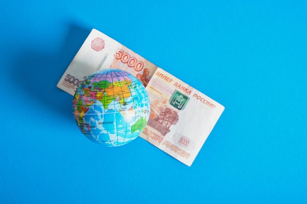 Model of the globe and a banknote of 5000 rubles blue background