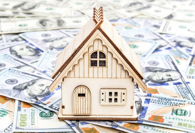 Model of house on background of dollar bills