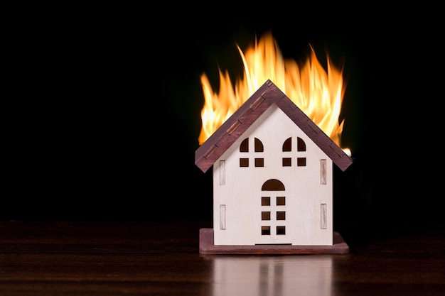 Photo model house in fire on black background with copy space