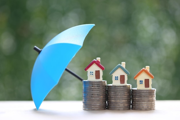 Model house on stack of coins money with the umbrella on nature green background