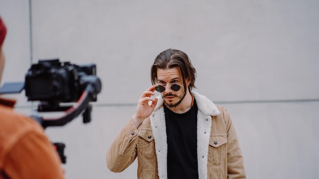 Model man looking through sunglasses and posing to the cameraman in urban street attractive male wor