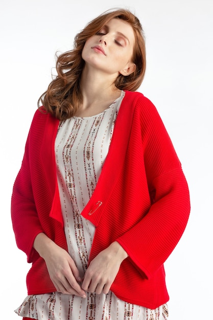 Model posing in a red sweater jacket and light blouse