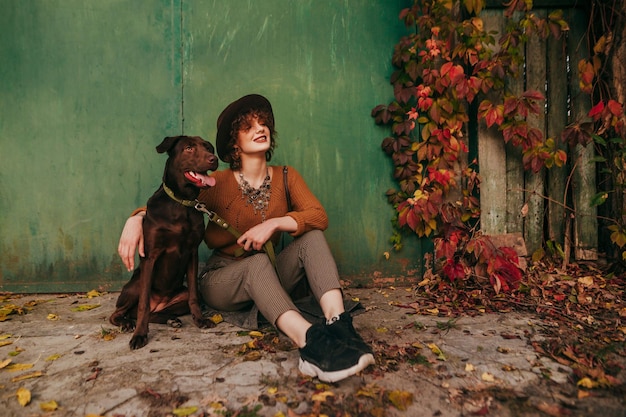 Model posing in village with dog on green grunge background with ivy