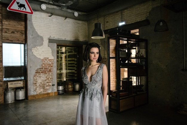 Model posing in a white long wedding dress indoors by the window. 