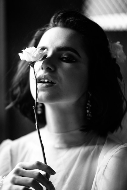 Model posing in a white wedding dress holds a flower in her hand