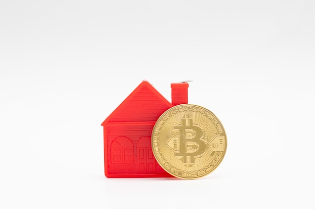 Model of red small house model and gold bitcoin coin on white