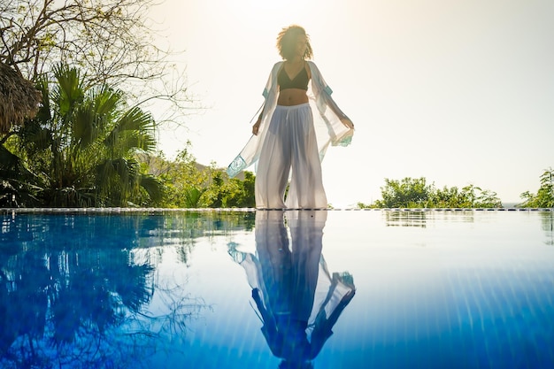 Model standing next to an outdoor tropical pool