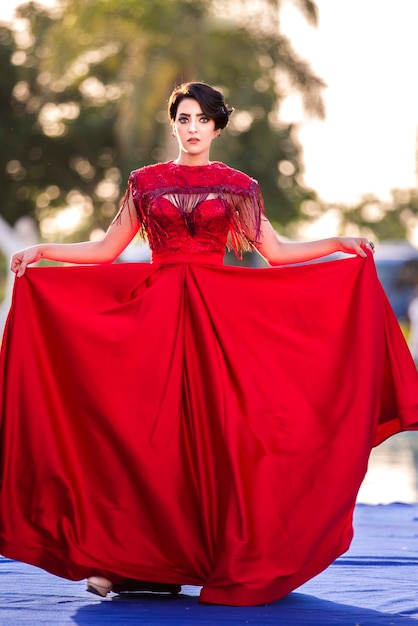 A model wears her red dress and lifts it with her hands during a fashion show on stage