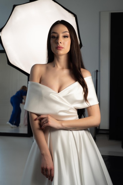 A model wears a white wedding dress in front of a mirror.