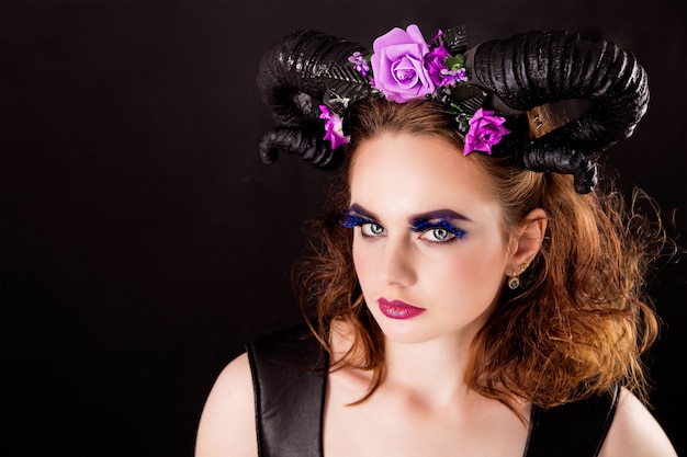 Model with fashion make-up and horns on the head on black 