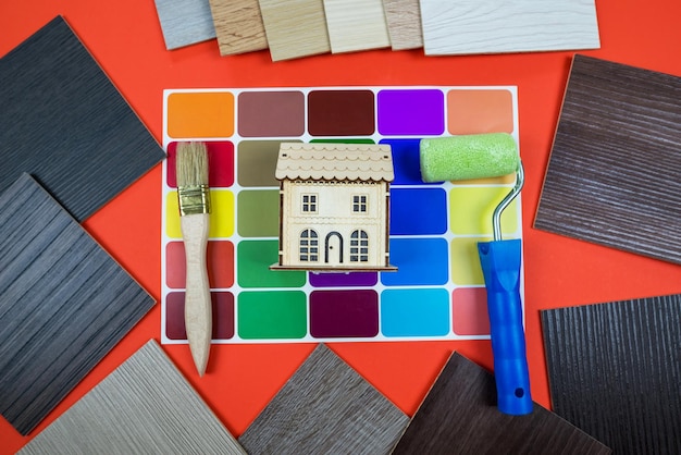 Model of a wooden house with a color palette and paint brushes