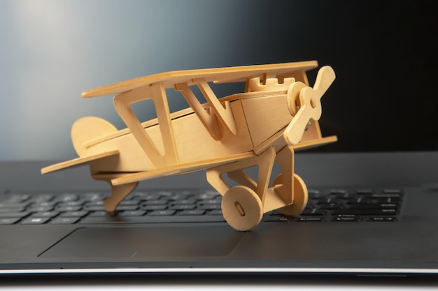 Model of a wooden plane on the background of a laptop Business development and success Dream to fly in your favorite business